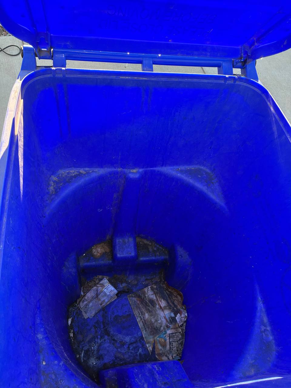 Before: dirty blue trash bin with debris stuck to the bottom